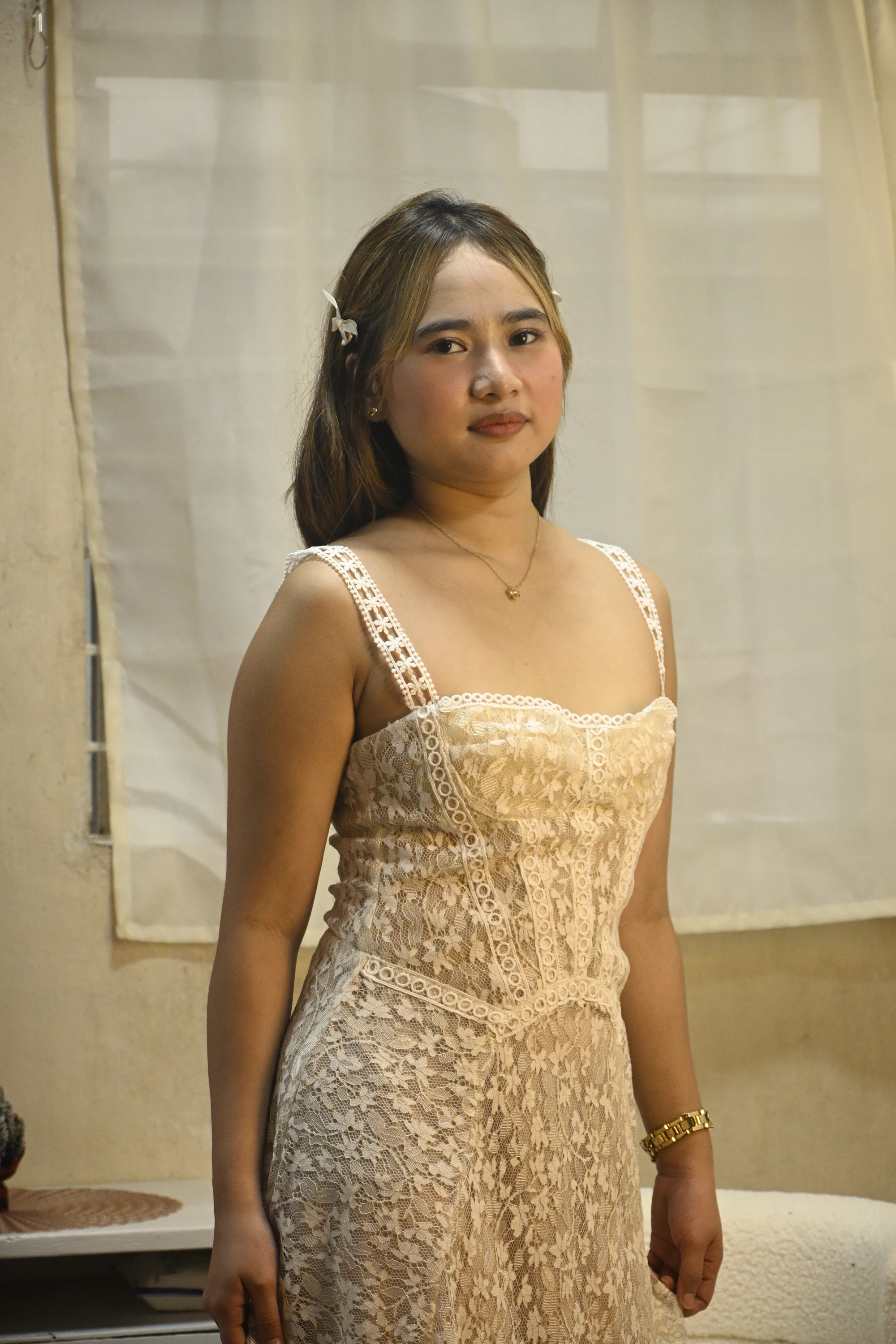 Closer front view of a cream lace dress with broad embellished straps, a square neckline and geometric trim.