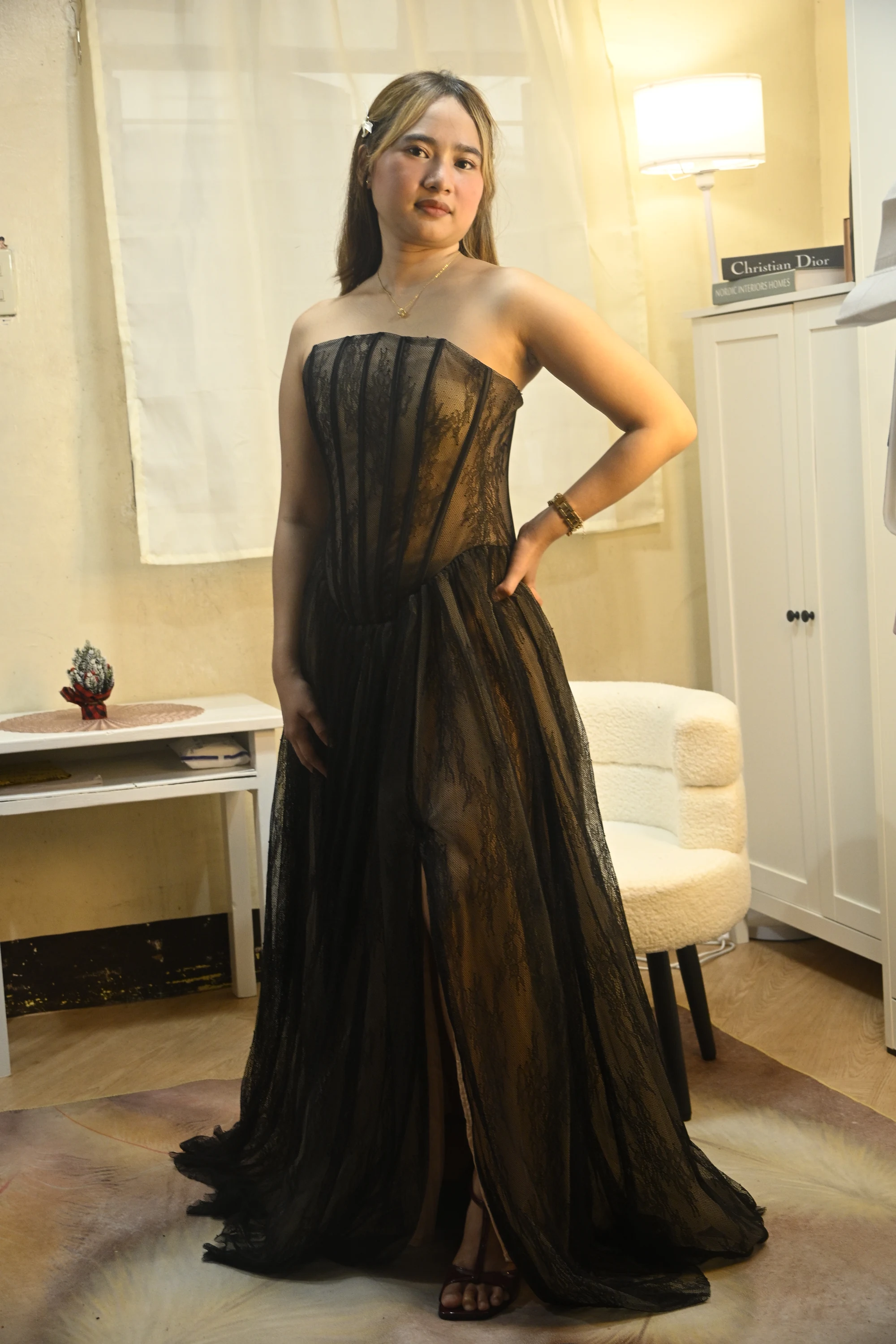 Full-length portrait of a model in a strapless black lace gown with a structured corset bodice and flowing skirt.