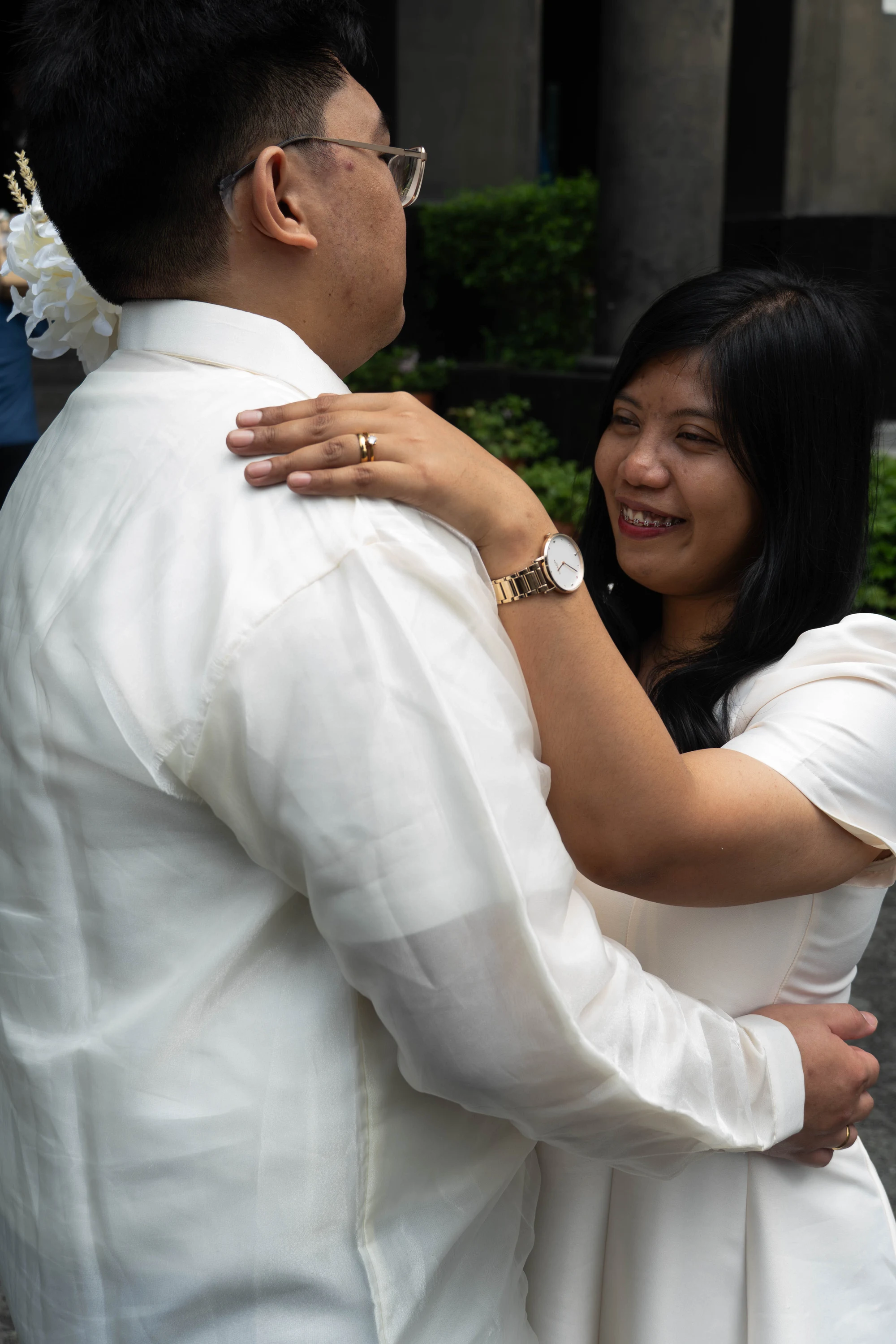 The bride smiles with her ringed hand resting on the groom’s shoulder.